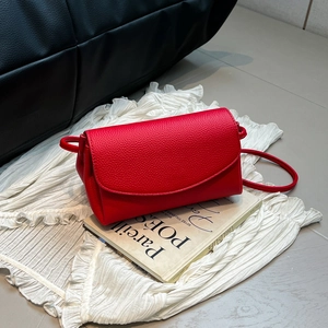 Gros plan d'un sac à bandoulière en cuir rouge à texture litchi avec rabat et sangle