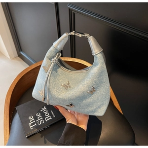 Detailaufnahme der hellblauen Denim-Hobo-Tasche mit 3D-Metall-Schmetterlingsverzierungen