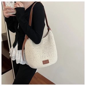 Detail of hand-woven cream cotton bucket bag featuring a brown leather strap and logo patch
