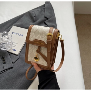 Close-up of quilted cream crossbody phone bag with brown leather trim and gold charm