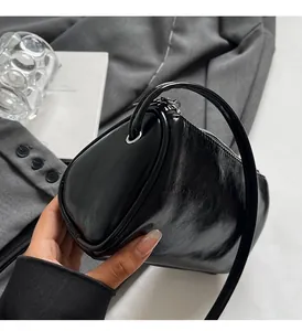 Detail der schwarzen glänzenden Zylindertasche mit Ledertextur und Metallreißverschluss