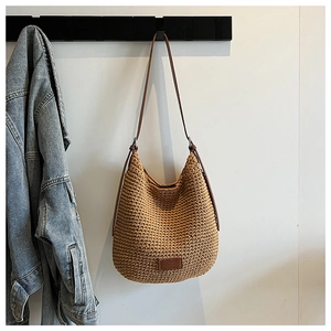 Detail of hand-woven cotton hobo bag with leather logo tag and brown strap on a hook