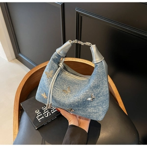 Detailansicht der blauen Denim-Achseltasche mit silbernen Schmetterlingen und Fransen