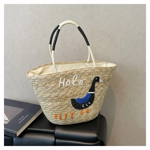 Detail of hand-woven straw tote with goose embroidery and stitched Hala lettering