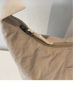 Dettaglio di una borsa tote in nylon beige con superficie strutturata e cerniera bianca