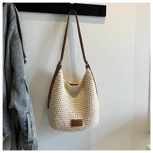 Detail of hand-woven cotton hobo bag with brown leather strap and brand patch