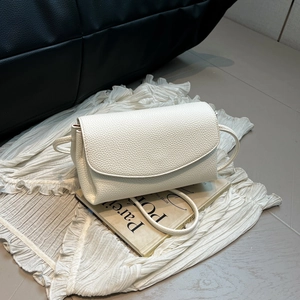Vue détaillée de la texture du cuir blanc crème à motif litchi sur un sac bandoulière