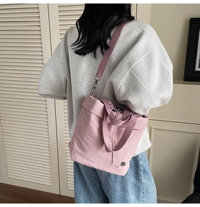 Detail of light pink nylon tote bag with side drawstring and adjustable strap on a model