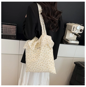Détail du sac cabas en toile à fleurs avec bordures volantées porté à l'épaule