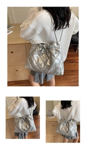 Detailed view of silver metallic bucket bag with quilted patterns and star rivet studs