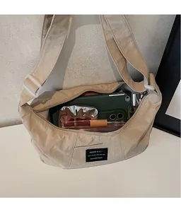 Vista dall'alto della borsa a mezzaluna beige capiente con tablet e trucchi all'interno