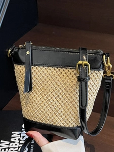 Fashionable straw bucket bag with black leather accents and adjustable strap for summer