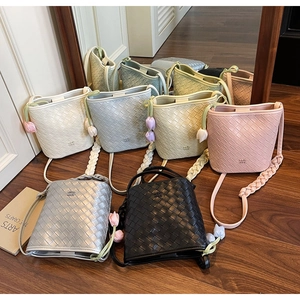 Detailed close-up of colorful woven bucket bags with leather floral charms on wood floor