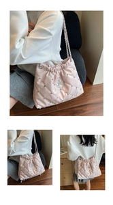 Detail view of light pink quilted bucket bag with silver stars, rivets and chain straps