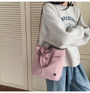 Detailed shot of pink nylon drawstring tote bag with adjustable strap and metal logo