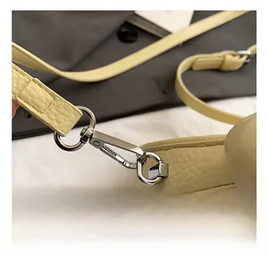 Close-up of beige lychee grain leather handbag featuring silver swivel metal hooks