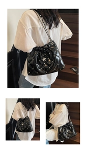 Detail of black quilted shoulder bag with silver star diamonds and chain strap shown in use