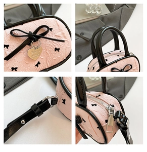 Détails du sac jacquard rose avec nœuds noirs, breloque coeur et finitions zippées