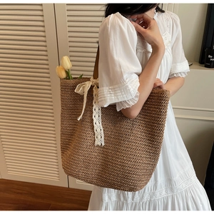 Detail of woven straw tote bag featuring white lace ribbon bow and large capacity design