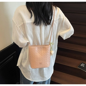 Detail of pink woven leather crossbody bucket bag with a tulip flower charm and strap