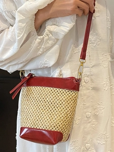 Fashionable straw crossbody bucket bag with dark red leather trim and tassel detail