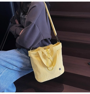 Detail view of yellow nylon tote bag with drawstring closure and metal plate