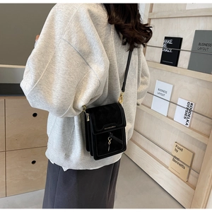 Detail view of the black crossbody phone bag with drawstring charm and gold hardware