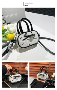 Détail du mini sac blanc avec motifs de nœuds noirs et pendentif en forme de cœur