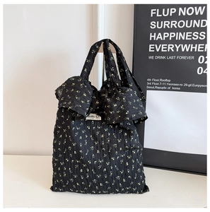 Gros plan du sac cabas floral noir avec texture plissée et grands nœuds décoratifs