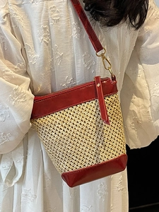 Fashionable woven straw bucket bag with red faux leather trim and golden metal hooks