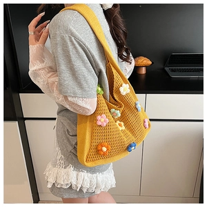Detail of hand-woven yellow knit shoulder bag featuring 3D colorful crochet flower patterns