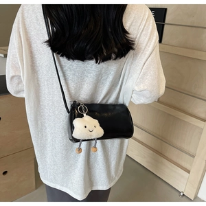Detailaufnahme einer schwarzen Zylindertasche mit einem flauschigen weißen Wolkenanhänger