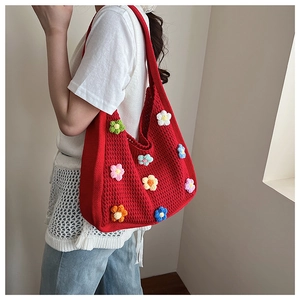 Detail of red handmade crochet tote bag featuring colorful 3D knitted flower accents