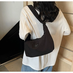 Detailed view of a black nylon crossbody bag with an adjustable strap on a female model