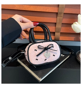 Gros plan d'un mini sac rose froncé avec broderie nœud et plaque en forme de cœur