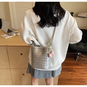Detail view of woven metallic silver bucket bag with a pink tulip floral pendant