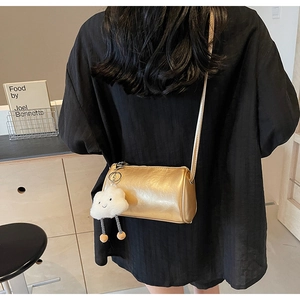 Details einer schicken goldenen Zylindertasche mit einem weichen weißen Wolkenanhänger