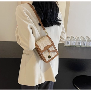 Detailed view of cream PU crossbody bag featuring brown leather trim and gold chain strap