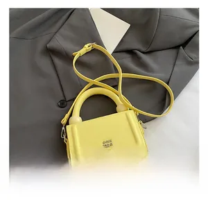 Detail of yellow pebbled leather bag with gold hardware and circular handle links