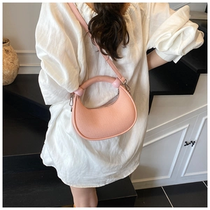 Detail of pink crescent bag showing vertical embossed texture and silver metal buckles