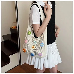 Detailed close-up of a white hand-knitted tote bag with colorful crochet flower patterns