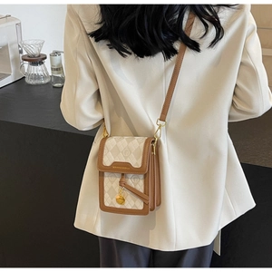 Detail view of mini vintage crossbody bag with jacquard pattern and gold metal pendant