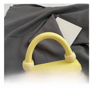 Detail view of yellow lychee leather handbag handle with round ball ornament and silver hardware