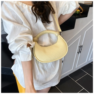 Detail of light yellow crescent handbag with vertical texture and round top handle