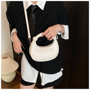 Detail of white half-moon bag with croc texture and decorative ring handle shown by model