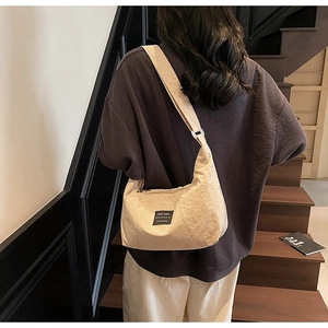 Rear view of a model wearing the cream-colored crescent bag on a modern staircase