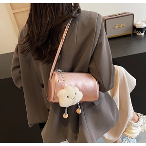 Detail der roségoldenen Zylindertasche mit einem niedlichen weißen Plüschwolken-Anhänger