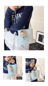 Detail van een lichtblauwe geweven emmertas met een schattige cartoon pop als accessoire