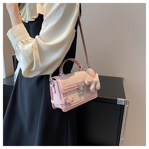 Close-up of pink leather crossbody bag with silver butterfly buckle and rabbit charm