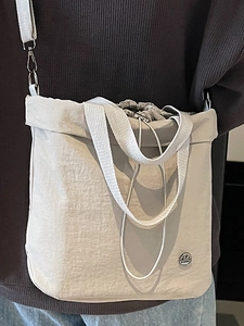 Chic beige bucket bag with drawstring closure and wide fabric shoulder strap